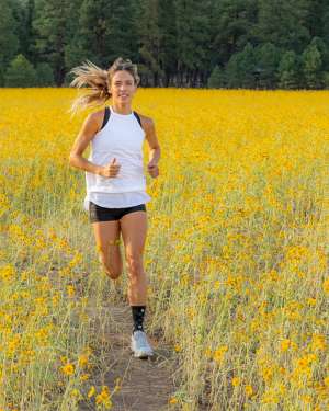 Fit woman trail running through a meadow of yellow sunflowers near Flastaff Arizona
