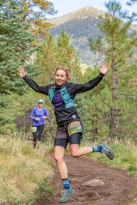 Woman runner atheltically jumps in a mountain trail race