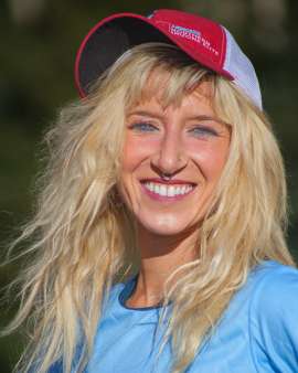 Smiling blonde female athlete with a nose ring wearing a red baseball cap