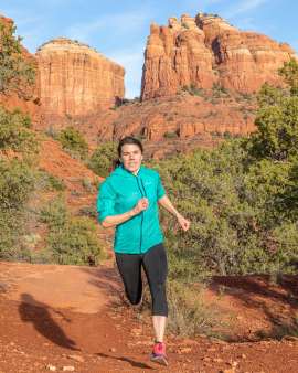 Woman trail running along a red rock trail near Sedona Arizona